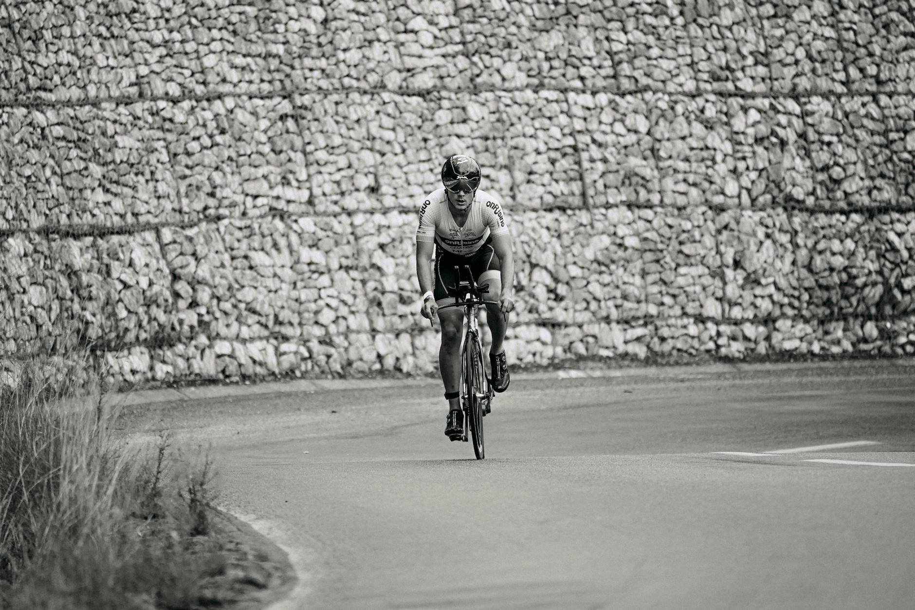 Kolarz jedzie w stroju sportowym wzdłuż kamiennego muru