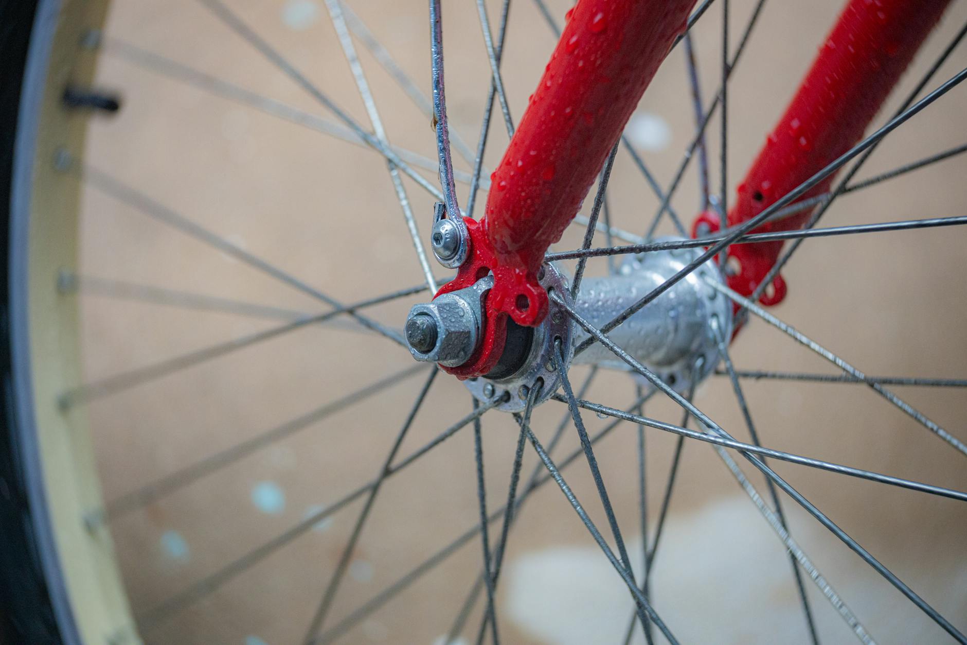 Mokre koło roweru z widocznymi szprychami i czerwoną ramą po deszczu